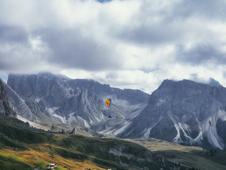 Paraglider in flight on the side of Mount Seceda in Dolomites, Italyの写真素材
