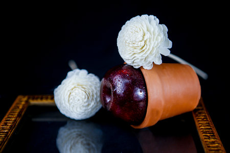 Still life with an apple and white flowers on a black background.の写真素材