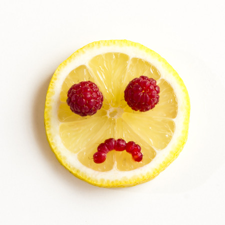 Sad eyes of lemon with raspberries on a white .の写真素材