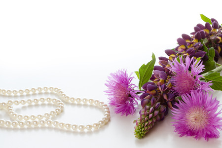 Bouquet of garden flowers and a pearl necklace on a white background.の写真素材