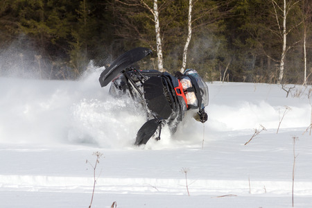 Athlete makes a sharp turn on a snowmobile in the winter woods in deep snowdrifts.の写真素材