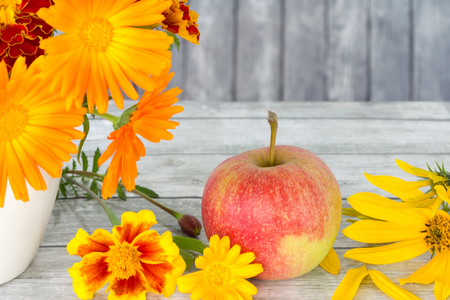 Autumn still life with marigolds and apples on wooden background.の写真素材