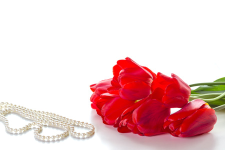 Bouquet of red roses and a pearl necklace on a white background.の写真素材