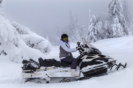 Woman on a snowmobile moving in a winter forest in the mountains of the Southern Urals.の写真素材