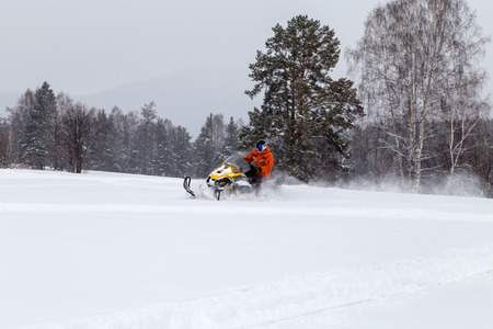 Athlete on a snowmobile moving in the winter forest in the mountains of the Southern Urals.