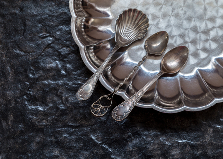 Still life with old spoons and a metal plate on a stone background.の写真素材