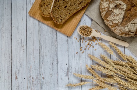 Whole-wheat bread and wheat ears on a wooden table.