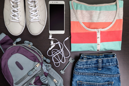 Women's sportswear on a light background. Sports female T-shirt with sneakers, phone, headphones. View from above. The concept of a healthy lifestyle.の写真素材