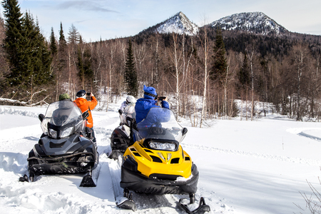 Athletes travel by snowmobile through the mountains of the South Urals and photograph mountains on a smartphone.の写真素材