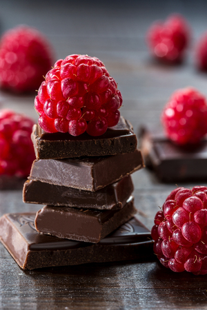 Raspberries and broken chocolate on a dark background.の写真素材