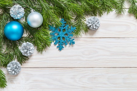 Spruce branches with Christmas ornaments on the wooden background.