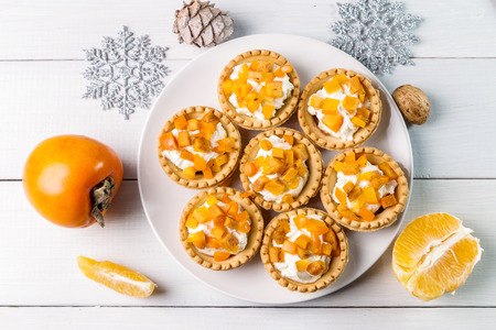Tartlets with curd cream and persimmon on a light background.の写真素材
