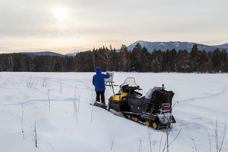 A woman arrived on a snowmobile in the mountains of the Urals to write a beautiful landscape.の写真素材