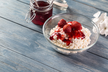 Cottage cheese with jam and strawberry on a wooden table.の写真素材