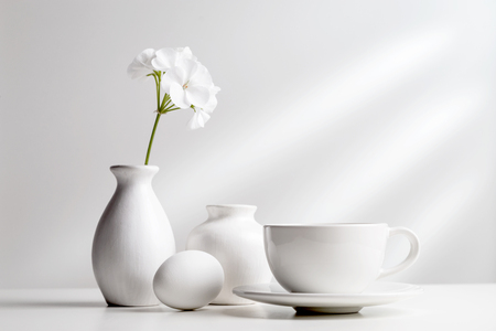 White dishes and a flower in a vase on a light background.の写真素材