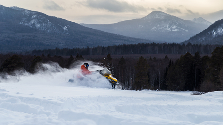 Athlete on a snowmobile moving in the winter forest in the mountains of the Southern Urals.