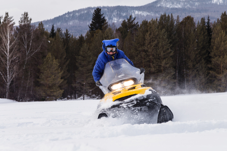 Woman on a snowmobile moving in the winter forest in the mountains of the Southern Urals.の写真素材