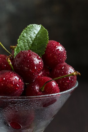 Fresh sweet cherry with water drops in a transparent glass.の写真素材