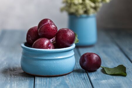 Plums in a blue bowl on a wooden background.の写真素材