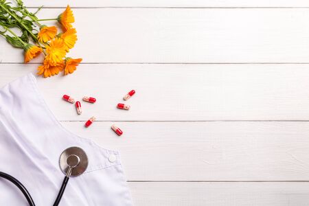 Stethoscope, pills and calendula flowers on a wooden background.の写真素材