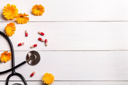 Stethoscope, pills and calendula flowers on a wooden background.の写真素材