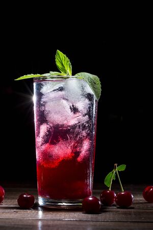 Cherry lemonade with ice in a transparent glass on a dark background.の写真素材