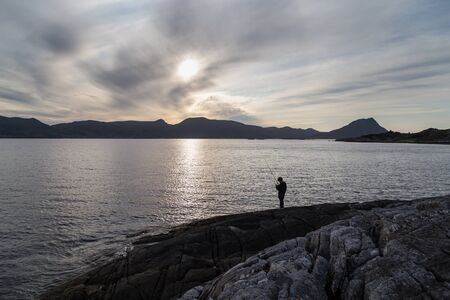 A boy is fishing in a fjord in Norway.の写真素材