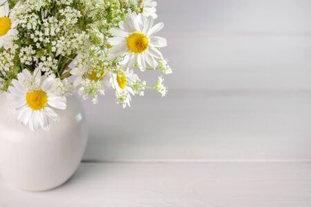 Bouquet of wildflowers in a white vase on a light background.の写真素材