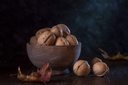 Walnuts in a wooden bowl on a dark background.