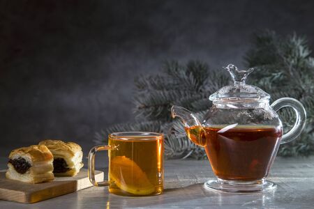 Hot tea with lemon in a transparent bowl and a croissant on a dark background.の写真素材