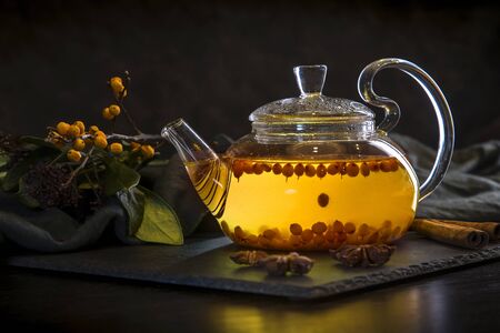 Hot sea buckthorn tea in a teapot on a dark background.の写真素材