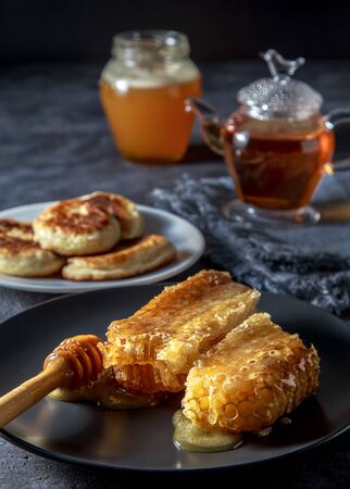 Honey and honeycombs with pancakes on a dark background.の写真素材
