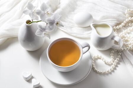 Tea in a cup and a white orchid on a white background.の写真素材