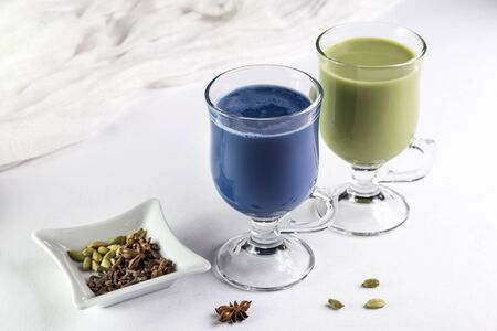 Green and blue traditional oriental matcha tea in a transparent glass cup on a white table with copy space.の写真素材