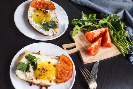 Sandwich with fried egg and tomato on a plate on a dark background.の写真素材