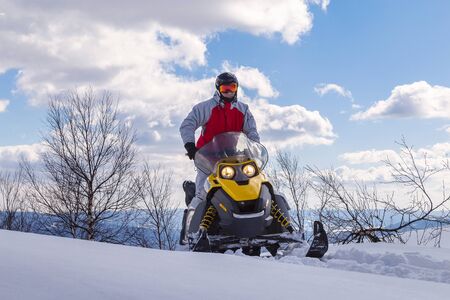 Athlete on a snowmobile moving in the winter forest in the mountains of the Southern Urals.