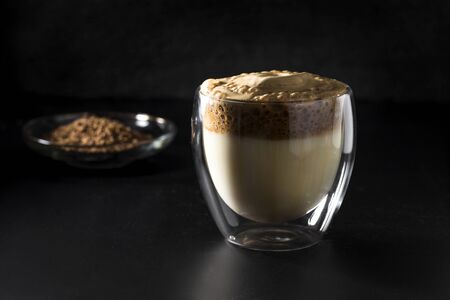 Iced Dalgona Coffee, fashionable fluffy creamy whipped coffee on a dark background.