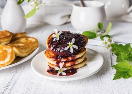 A stack of fritters with black currants on a plate on a light background.の写真素材