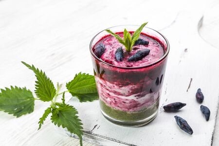 Delicious dessert with a layer of yogurt, smoothie with nettle and honeysuckle. Dessert served in a glass with a spoon.の写真素材