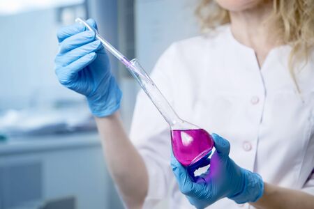 Scientist or doctor in lab coat with test tube with reagent. Laboratory glassware containing chemical liquid.の写真素材