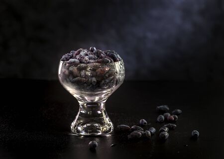 Honeysuckle berries in a glass vase on a dark background.の写真素材