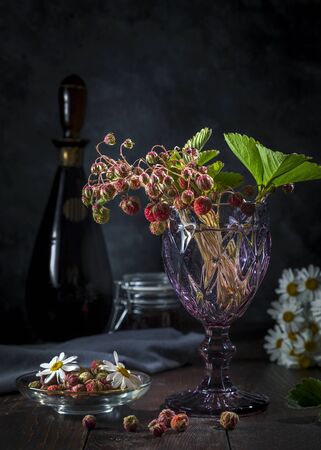 A bouquet of forest strawberries in a glass, on a dark background.の写真素材