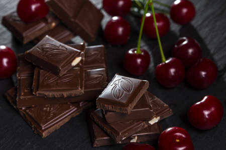 Cherries and broken chocolate on a dark background.の写真素材