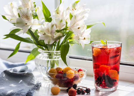 Berry drink and a bouquet of alstroemeria on the windowsill.の写真素材