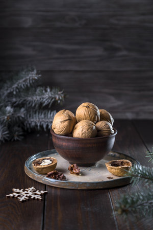 Walnuts in a clay bowl and spruce branches on a dark wooden background.の写真素材