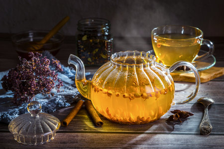 Hot sea buckthorn tea in a teapot on a wooden table.の写真素材