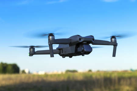 An unmanned aerial vehicle flies in the air low above the ground.