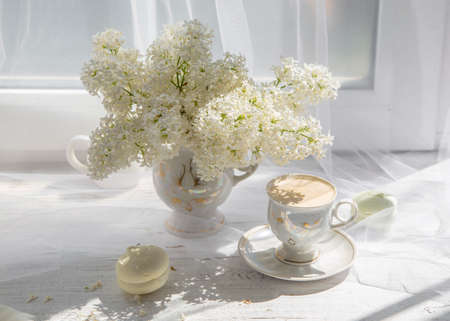 White lilac cup with coffee on the windowsill.の写真素材