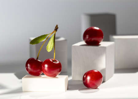 Modern still life with cherries and white cubes on a light background.の写真素材