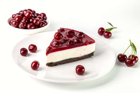 A piece of cherry cheesecake on a plate on a white table.